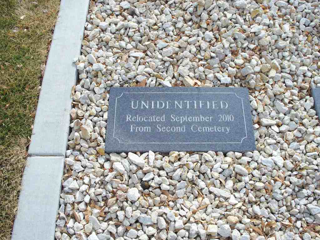 A memorial headstone planted in white gravel. The marker reads, "Unidentified. Relocated September 2010 from Second Cemetery."